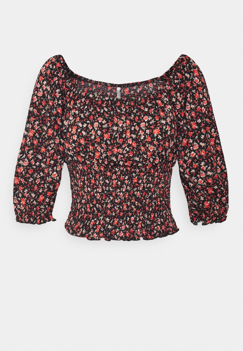 Blouse courte noire avec imprimé floral rouge et blanc, taille smockée, manches trois-quarts bouffantes et encolure carrée.