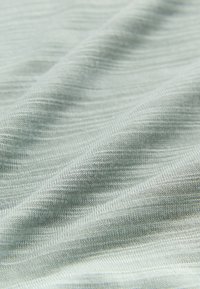 Heleroheline, pehme tekstiil peene soonilise tekstuuriga. Kangas tundub sile ja veidi läikiv, näidates õrnaid voltte ja kortse.