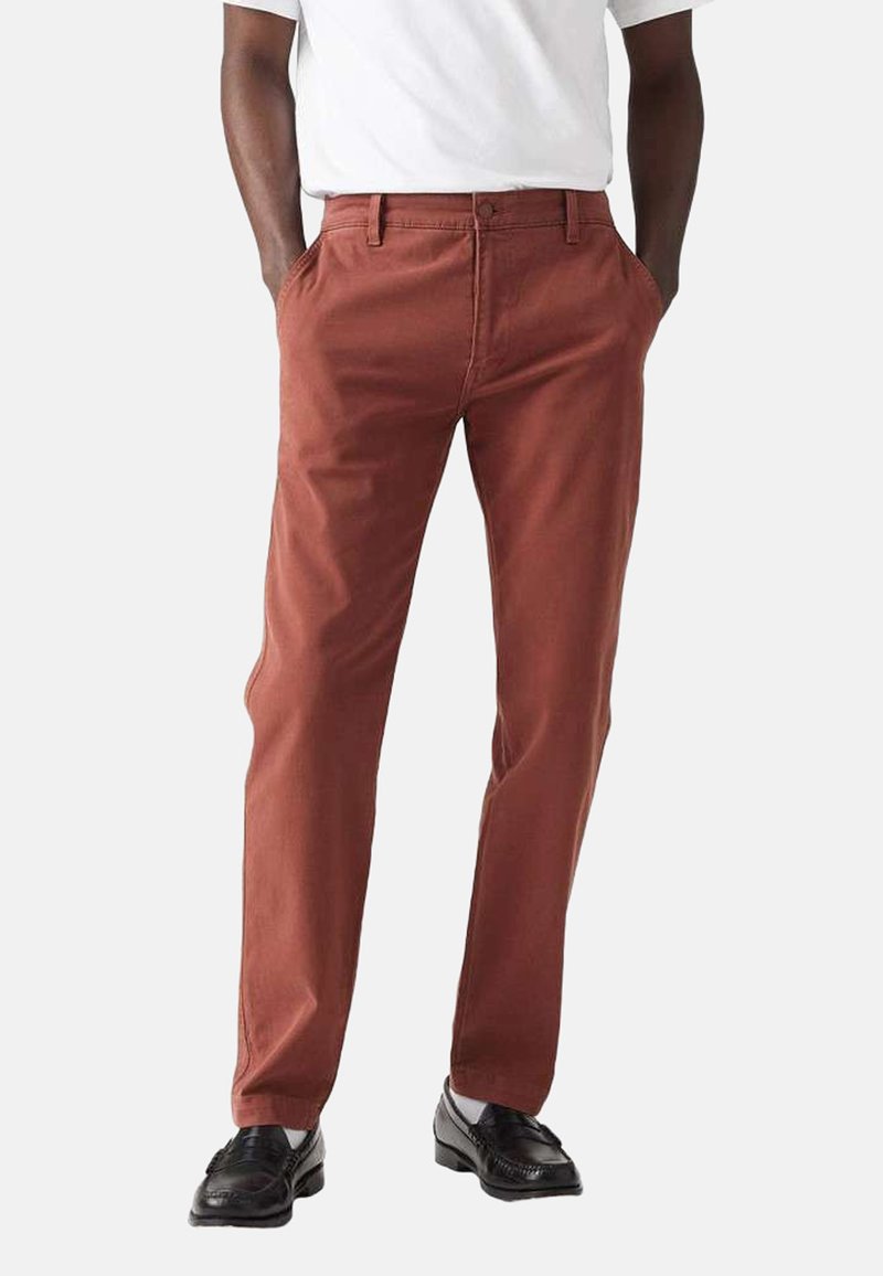 Mørk rustfarvede bomulds chinos med sidelommer, lige ben design og en glat overflade. Udstyret med bæltestropper i taljen og minimal syning.