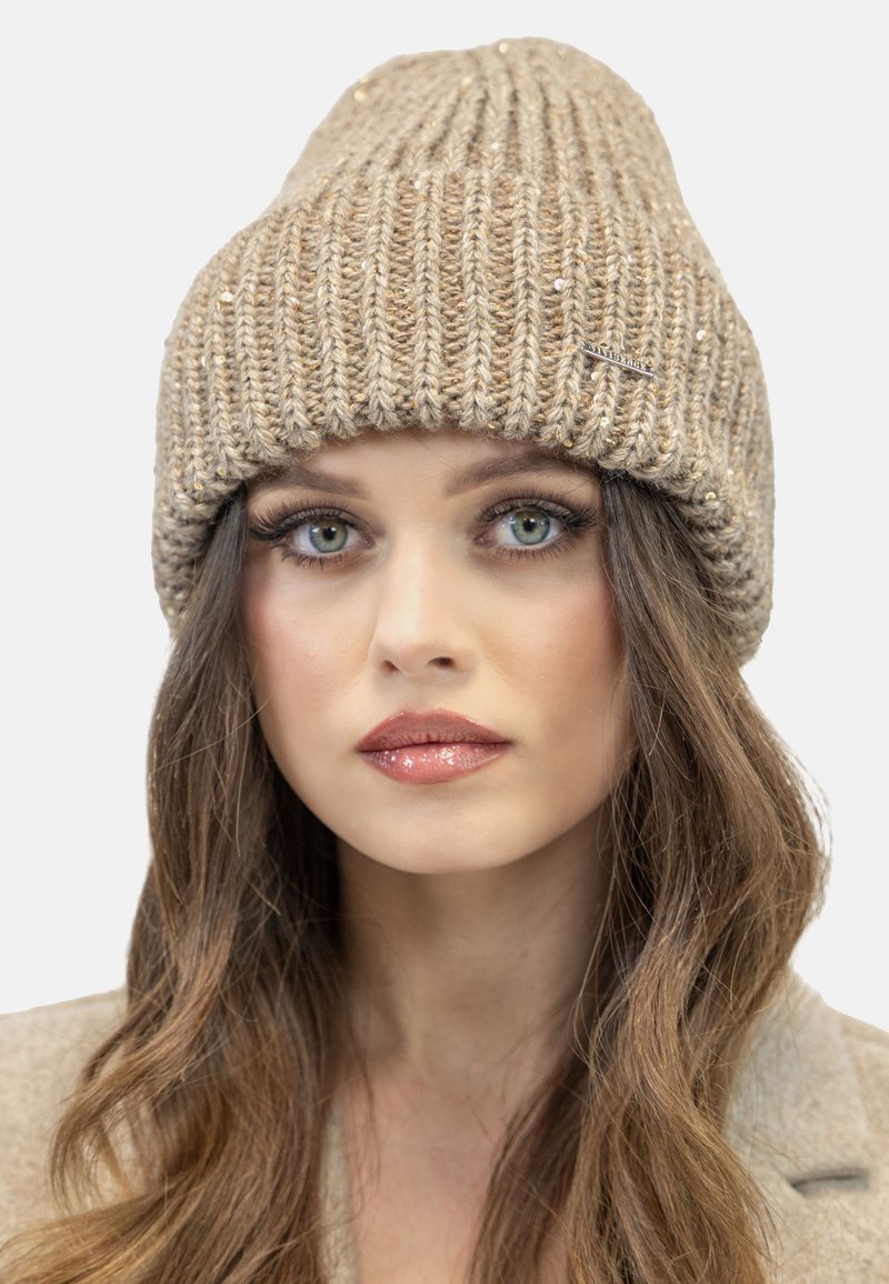 Beige gebreide beanie met een geribbelde textuur, voorzien van subtiele gouden spikkels. Inclusief een klein metalen logoaccent aan de zijkant.