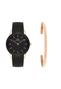 Daniel Wellington laikrodis turi juodą silikono dirželį, apvalų juodą ciferblatą, auksinius valandų žymeklius ir ploną auksiniu akcentuotas apyrankę.