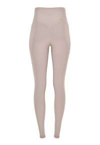 Leggings a vita alta in un tessuto beige chiaro con una texture liscia, caratterizzati da un sottile dettaglio di cucitura curva e un piccolo logo dorato.