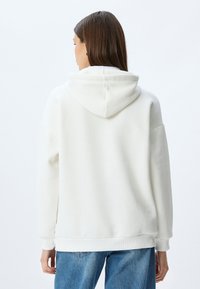 Witte hoodie met een ontspannen pasvorm, voorzien van ribgebreide manchetten en zoom. Gladde textuur, zonder zichtbare patronen of accenten.