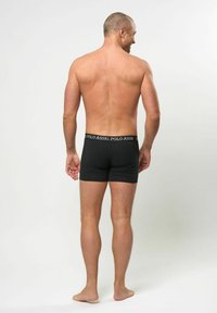 Svarta boxerkalsonger med resårmidja och vit logotyptext. Tyget är slätt och åtsittande, med en minimalistisk design.