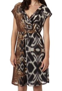 Robe à manches courtes avec un col drapé, confectionnée dans un tissu léger arborant un motif abstrait marron, noir et blanc. Taille élastique.