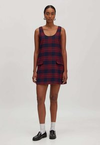 Kariert Kleid in Rot und Marineblau mit einem Rundhalsausschnitt, zwei Vordertaschen und ärmellosem Design, aus einem strukturierten Stoff gefertigt.