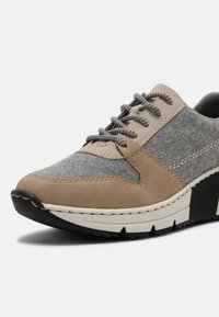 Sneakers beige e grigi con texture, caratterizzati da pannelli in feltro e pelle, lacci grigi e una suola in gomma nera con accenti bianchi.
