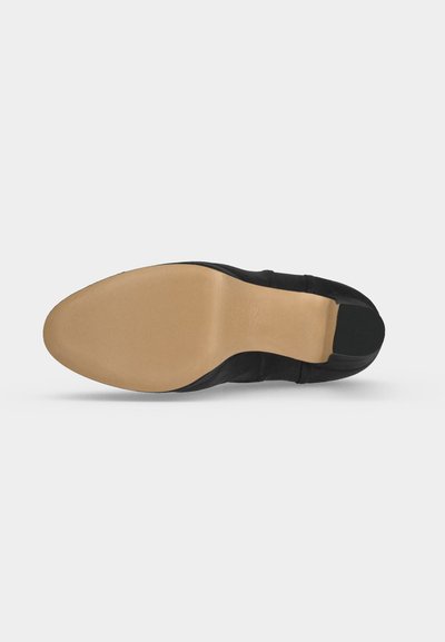 Semelle d'une chaussure habillée en cuir noir à bout pointu avec une semelle beige lisse et une partie talon noire.