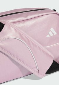 Pink synthetic fabric bag with textured surface, white accents, and a black strap. Features include a zip closure and diagonal stitching.