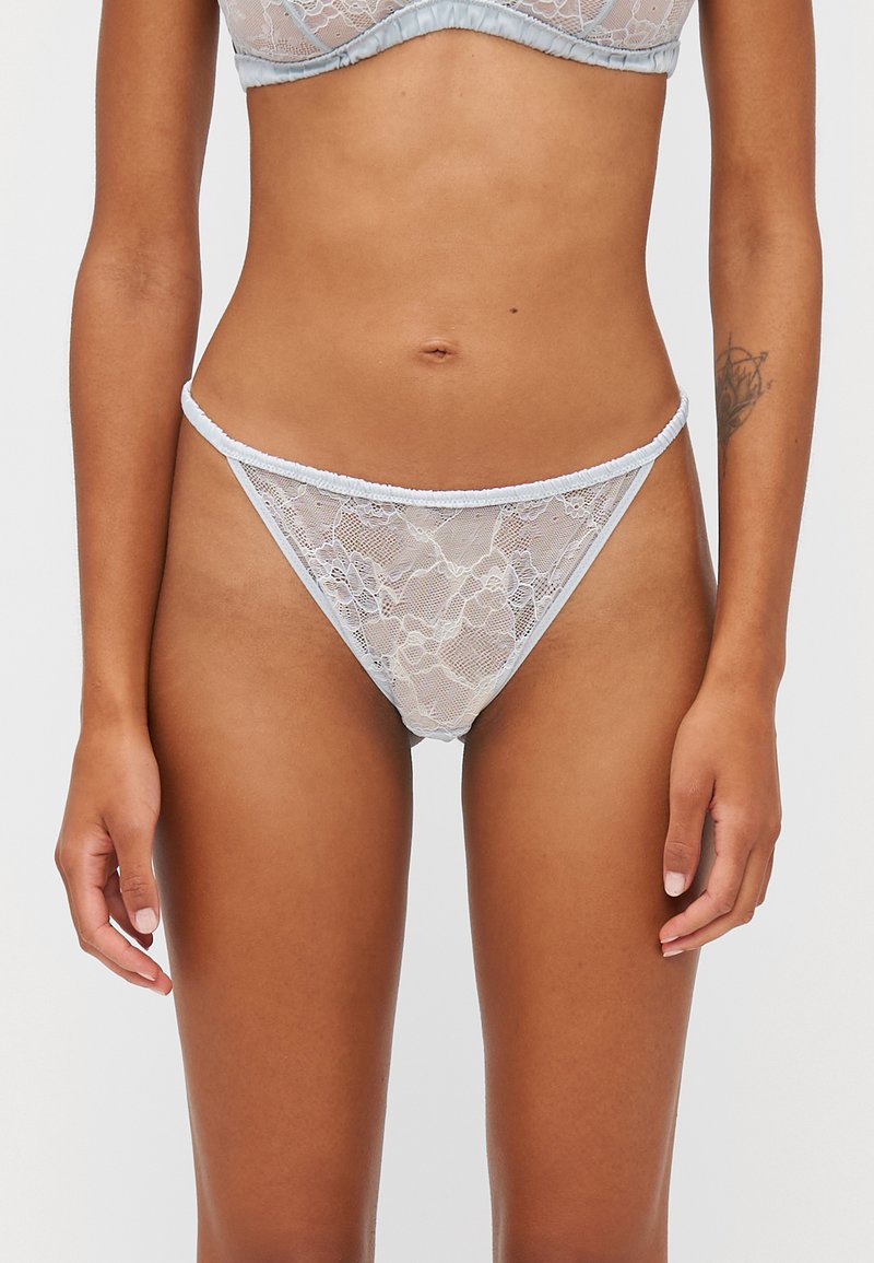 Sinih lace thong yang menampilkan pola bunga, tekstur lembut, dan tali elastis tipis di sekitar pinggang dan kaki.