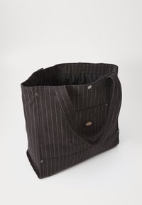 Crna platnena torba s bijelim prugama; sadrži čvrste ručke, zatvaranje na dugme i mali logotip sa strane.