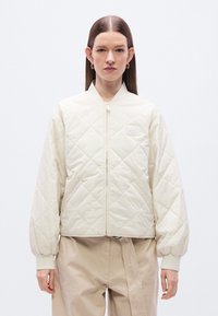 Κουκούλα  μπουφάν σε ανοιχτό κρεμ χρώμα με ριμπ μανσέτες και όρθιο γιακά. Διαθέτει μπροστινό φερμουάρ και διακριτική λεπτομέρεια με λογότυπο.