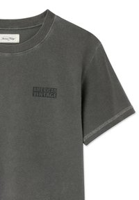 T-shirt gris charbon à manches courtes et col rond avec l'inscription « American Vintage » imprimée sur le côté gauche de la poitrine et des surpiqûres visibles sur les ourlets des manches.