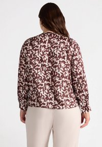Camicia a maniche lunghe con un motivo astratto marrone, bianco e rosa, dalla vestibilità comoda e con polsini con bottoni. Tessuto morbido e leggero.
