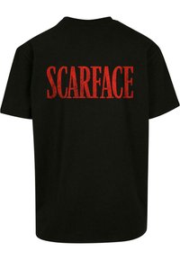 Juoda medvilninė marškinėlių su ryškiai raudonu tekstu "SCARFACE" ant nugaros. Trumpomis rankovėmis ir klasikinio kirpimo. Be papildomų dizainų ar akcentų.