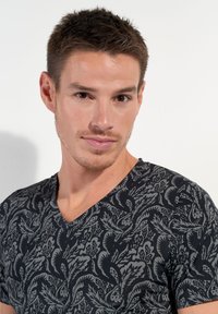 V-neck t-shirt in black with intricate gray floral patterns, made of soft fabric; fitted design accentuates the neckline.