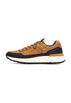 Zapatillas de ante marrón claro con detalles negros y suela blanca salpicada. Los cordones redondos y el collar acolchado ofrecen contraste y soporte.