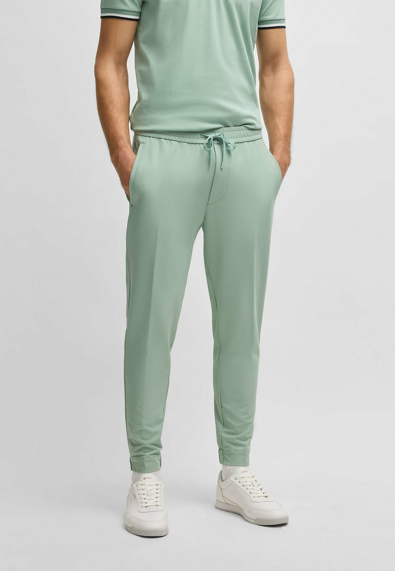Muntgroene joggers met een elastische tailleband, trekkoord en zijzakken. Gecombineerd met witte sneakers voor een casual look.