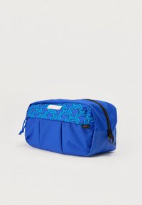 Μπλε υφασμάτινη θήκη με εμπριμέ μπλε και πράσινο πάνω μέρος, φερμουάρ, μπροστινές πτυχώσεις και μικρό ταμπελάκι με λογότυπο. Συμπαγής και δομημένος σχεδιασμός.