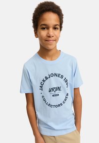 Camiseta de algodón azul claro con un gráfico circular negro que incluye el texto "JACK&JONES 1990 URBN. COLECCIONISTAS CREW". Mangas cortas, cuello redondo.