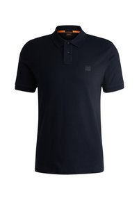 Polo en coton marine, avec un plastron à deux boutons, des manches courtes, et un logo en patch texturé sur la poitrine.