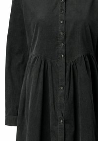 Rochie din catifea neagră cu mâneci lungi, închidere cu nasturi în față și talie strânsă. Prezintă o textură subtilă și accesorii din nasturi metalici.