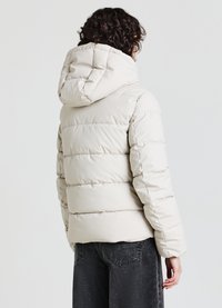 Giacca imbottita beige chiaro con cappuccio, caratterizzata da pannelli diagonali trapuntati e polsini elasticizzati, realizzata in materiale liscio e lucido.