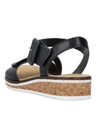 Black leather sandal with a cork base, adjustable strap, and white detailing. Open back design with a textured sole.