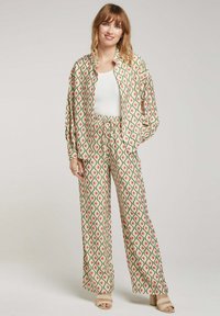 Ensemble de pyjama à motifs avec un design en diamants vert, rose et crème ; coupe ample, manches longues, taille élastique et texture douce.