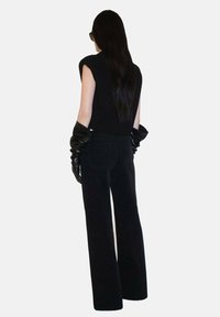 Haut sans manches en tricot noir avec une silhouette ajustée, associé à un pantalon large taille haute noir et des gants longs et brillants noirs.