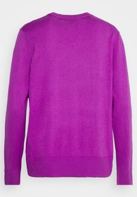 Bakvy av en enkel lila crewneck-tröja med lång ärm och ribbade muddar och nederkant mot en vit bakgrund.