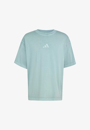 Lyseblå oversized t-skjorte laget av mykt stoff. Har rund hals og et lite hvitt Adidas-logo på brystet. Korte ermer.