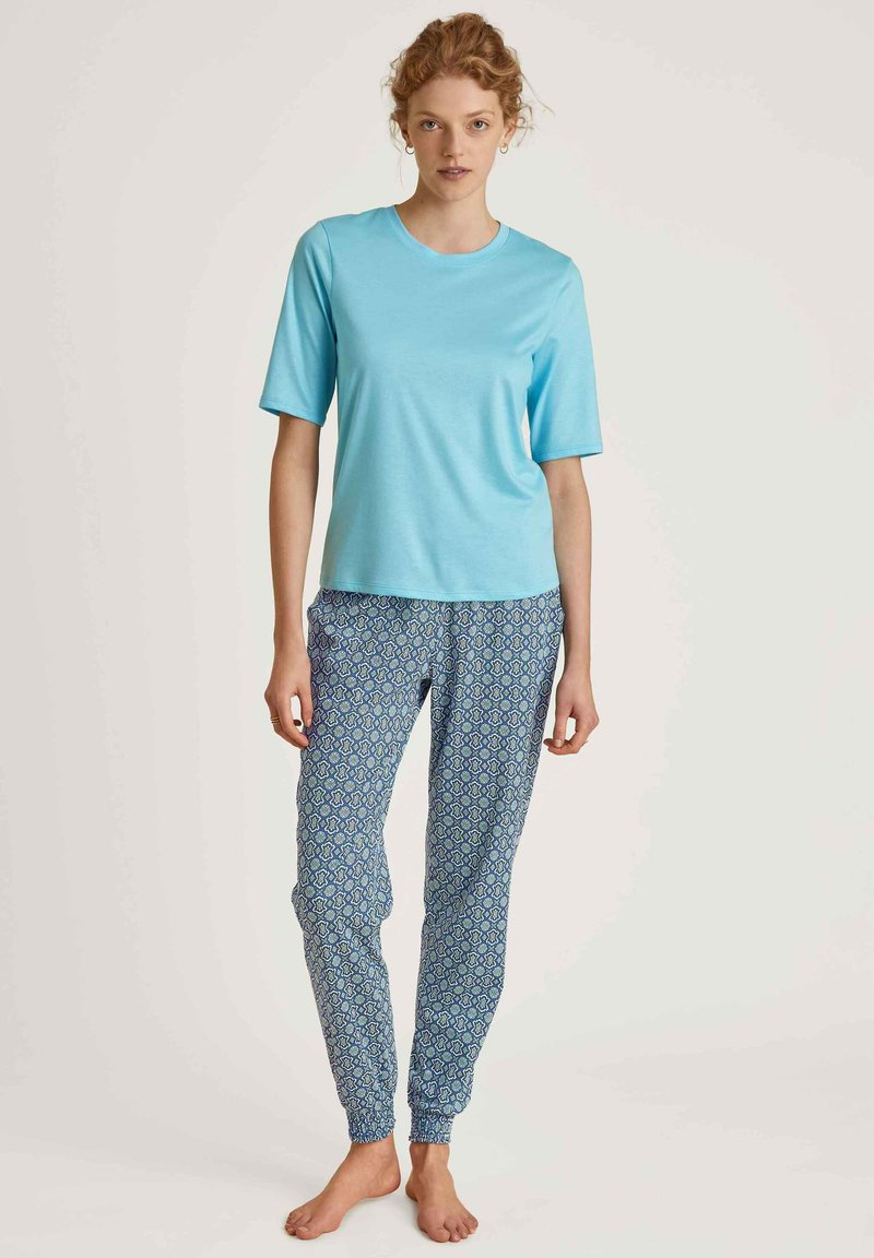 Lichtblauw shirt met korte mouwen, gecombineerd met gestreepte blauwe pyjamapantalons met elastische boorden en een geometrisch ontwerp.