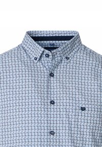 Koszula zapinana na guziki w jasnoniebieskim kolorze z geometrycznym wzorem w granatowym. Posiada kołnierz, dwa guziki na plisie oraz małe haftowane logo.