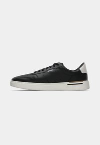 Baskets basses noires avec semelle blanche et accent au talon, fermeture à lacets et logo "BOSS" sur le côté.