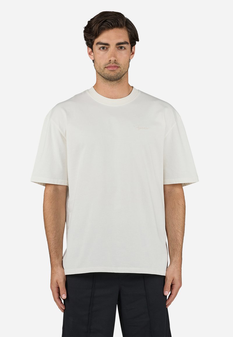 Tricou alb din bumbac, cu o croială lejeră, mâneci scurte, decolteu rotund și un logo brodat subtil pe piept. Textură netedă.