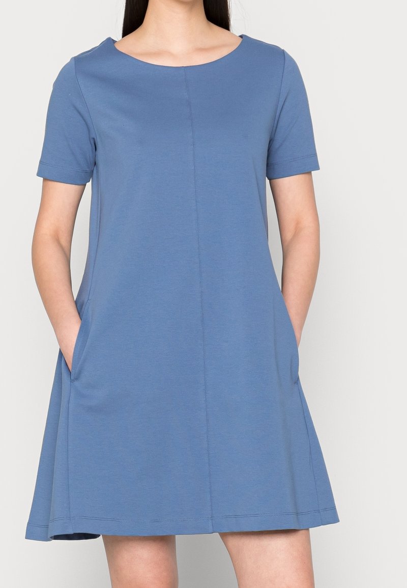 Niebieska sukienka z krótkim rękawem, okrągłym dekoltem, rozkloszowanym fasonem i kieszeniami bocznymi. Wykonana z miękkiej tkaniny bawełnianej z dodatkiem wiskozy. Proste wykończenia szwów.