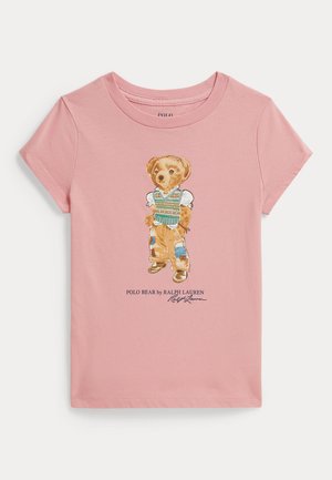 Różowy T-shirt z krótkim rękawem z grafiką stojącego niedźwiedzia w kamizelce, załatanych spodniach i butach, z napisem Polo Bear by Ralph Lauren.