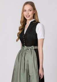 Schwarzes Kleid mit strukturiertem Oberteil, weißer Bluse und grünem Satin-Schürzen mit gebundenem Bogen. Verfügt über silberne Knöpfe und Spitzendetails an den Ärmeln.
