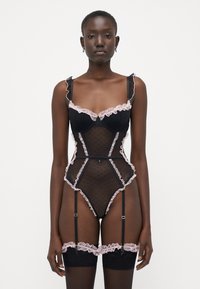 Lingerie nera con motivi a pois e dettagli in pizzo rosa. Presenta spalline arricciate, un design aderente e dettagli con reggicalze. Tessuto testurizzato.