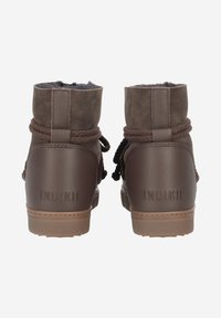 Bottes de cheville en suedine marron avec des accents en cuir, un col rembourré, des lacets en corde et un logo "INUIKII" sur le talon. Semelle extérieure en caoutchouc texturé.