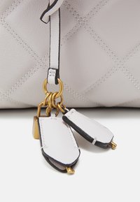 Sac à main en cuir gris clair avec un motif matelassé, doté de quincaillerie dorée et d'un détail de porte-clés suspendu avec des accents et des fermoirs noirs.