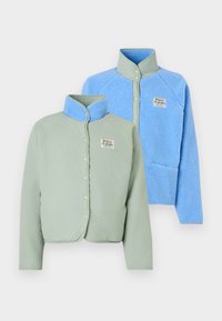Twee jassen: een muntgroene met een gladde textuur en drukknopen, en een lichtblauwe fuzzy fleece met een kraag en een logo-opdruk.