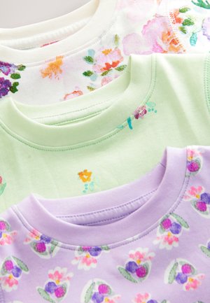 Kolm lühikeste varrukatega T-särki virnas. Ülemine: valge roosade lillemustriga. Keskmine: ühevärviline hele roheline. Alumine: helelilla mitmevärviliste lilledega.