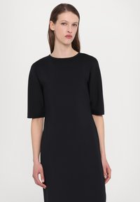 Čierne šaty s krátkymi rukávmi, okrúhlym výstrihom, vyrobené z hladkej látky, s minimalistickým dizajnom a rovnou siluetou.