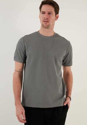 Tricou gri cu mânecă scurtă, design fără cusături, material texturat, decolteu reflectând o formă rotundă, cu un finisaj neted și o mică detaliere a logo-ului pe laturi.