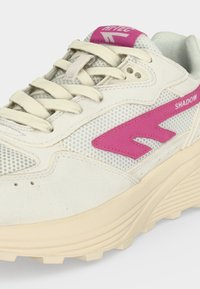 Λευκό και μπεζ αθλητικό παπούτσι με ροζ λογότυπο και κείμενο "SHADOW" στο πλάι, λευκά κορδόνια και υφασμένο πέλμα.