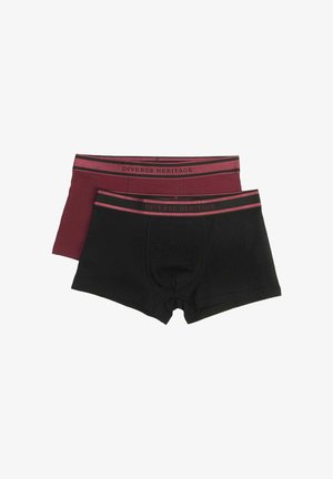 Dwa pary szortów: jedne czarne, drugie burgundowe. Obie mają kontrastowy pas z napisem "Diverse Heritage" oraz subtelne paskowe akcenty.