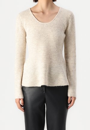 Sweater a coste color crema con scollo a barca, maniche lunghe e orlo svasato. Abbinato a pantaloni in pelle nera.