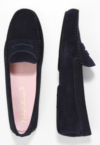 Mocassins en suède navy avec couture de style mocassin, bout arrondi et semelle intérieure rose. Présente un petit nœud décoratif à l'avant.